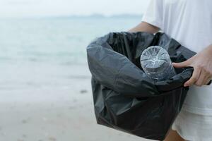 ahorrar agua. los voluntarios recogen basura en la playa y las botellas de plástico son difíciles de descomponer para evitar dañar la vida acuática. tierra, ambiente, planeta verde, reducir el calentamiento global, salvar el mundo foto