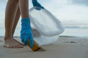 salvar océano. voluntario recoger arriba basura basura a el playa y el plastico botellas son difícil descomponer evitar daño acuático vida. tierra, ambiente, verdeado planeta, reducir global calentamiento, salvar mundo foto