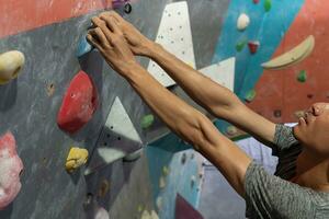 hombre alpinismo en pared formación en gimnasia, activo deportivo masculino practicando rock alpinismo en artificial rock en extremo deporte, búlder, alpinismo muro, trepador es capacitación, rock alpinismo en el ciudad, fuerte foto