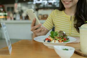 Woman use smartphone to scan QR code for order menu in cafe restaurant with a digital delivery. Choose menu and order accumulate discount. E wallet, technology, pay online, credit card, bank app. photo