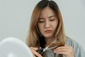 Asian woman very sad and upset looking at damaged hair, hair loss, hair thinning problem, vitamin deficiency, baldness, postpartum, biotin, zinc, menstrual or endocrine disorders, hormonal imbalance photo