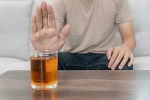 man refuses say no and avoid to drink an alcohol whiskey , stopping hand sign male, alcoholism treatment, alcohol addiction, quit booze, Stop Drinking Alcohol. Refuse Glass liquor, unhealthy, reject photo