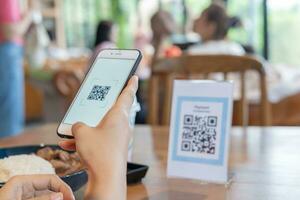 mujer utilizar teléfono inteligente a escanear qr código para orden menú en café restaurante con un digital entrega. escoger menú y orden acumular descuento. mi billetera, tecnología, pagar en línea, crédito tarjeta, banco aplicación foto