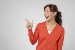 Portrait asian beautiful girl pointing blank space isolated background. Happy woman pointing on something. young female standing pointing finger sideways, billboard, introduction, advertisement, space photo