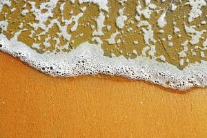 suave mar olas con un espuma rotura en un arenoso apuntalar tropical playa a verano a puesta de sol foto