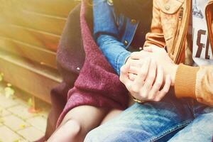 Couple hugging and holding hands sitting on a city park bench outdoors. photo