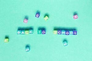 The inscription back to school made by multicolor plastic cubes on a blue green background. photo