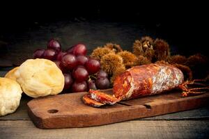 Close up chestnuts chorizo and grapes on rustic wooden table photo