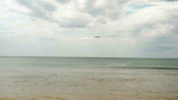 Slow motion, jet aircraft approaching to land. Passenger plane over the sea, cloudy sky, front view. Travel concept video