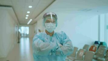 portrait de une infirmière homme avec franchi bras portant une visage masque et en mettant sur une visage bouclier à la recherche à le caméra dans une hôpital médical concept. video