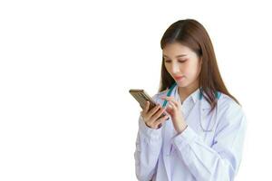profesional joven asiático mujer médico vistiendo blanco túnica en pie con utilizando inteligente teléfono para examinar reporte documento de paciente a plan siguiente tratamiento en hospital foto