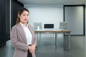 Portrait professional young Asian business woman who wears formal suit office worker is smiling working successful confidently with stands alone in the office room. photo