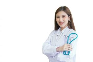 Professional young Asian woman doctor wearing white robe and stethoscope standing with arms crossed happy and smile at examination room in hospital in health concept while isolated on white background photo