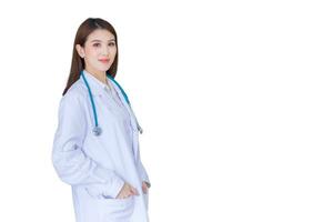 Professional Asian woman doctor standing with hand in pocket happy and smile in hospital wearing white robe and stethoscope. New normal and healthcare concept isolated on white background. photo