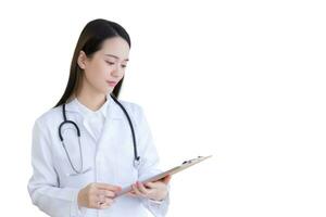 Young professional Asian woman doctor examine report document of patient to plan next treatment. She look at clipboard in her hand while working at hospital while working isolated on white background. photo