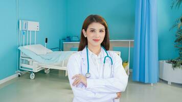 profesional joven asiático mujer médico vistiendo blanco túnica y estetoscopio en pie con brazos cruzado contento y sonrisa foto