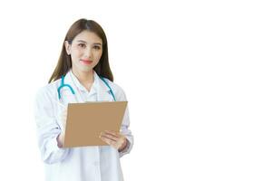 Young professional Asian woman doctor examine report document of patient to plan the next treatment. She look at the camera and clipboard in her hand while working isolated on white background. photo