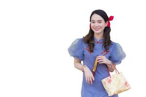 Young Asian girl in blue grey Chinese dress holds the paper bag  which screened word that means happy in Chinese and stands on while isolated on white background. photo