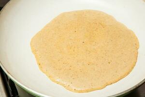 Quinoa crepes preparation. Cooking the quinoa crepes batter onto a frying pan photo