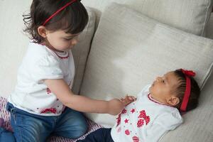 Big sister plays with her one month old baby sister at home. Love between sibblins concpet. Family concept. photo