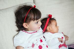 Big sister with her one month old baby sister at home. Love between sibblins concpet. Family concept. photo