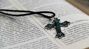 Close up shiny metal cross with black sling on old book to recall the kindness of Jesus Christ for all of Christian photo
