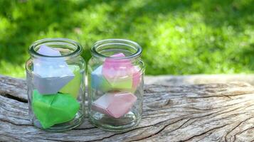 Paper hearts in glass bottles on wooden floor with blurred trees background concept for cheering LGBTQ people around the world photo