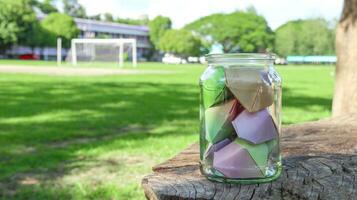 Paper hearts in glass bottles on wooden floor with blurred trees background concept for cheering LGBTQ people around the world photo