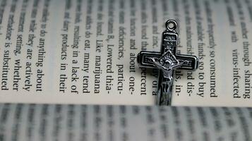 Close up shiny metal cross with black sling on old book to recall the kindness of Jesus Christ for all of Christian photo