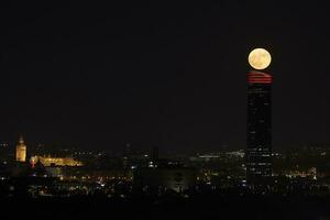 encantado noche en Sevilla. lleno luna, giralda, Sevilla torre, y plaza España visto desde camas foto