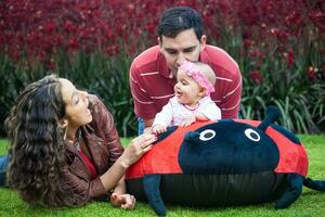 joven padres teniendo divertido al aire libre con su seis meses antiguo bebé muchacha. felicidad concepto. familia concepto foto