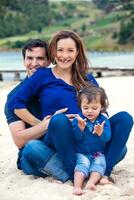 Young couple waiting for their second baby having fun with their baby girl at the beautiful white beach of Lake Tota located in the department of Boyaca at 3,015 meters above sea level in Colombia photo