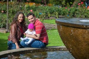 joven padres teniendo divertido al aire libre con su seis meses antiguo bebé muchacha. felicidad concepto. familia concepto foto