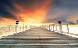 beautiful wood pier against dramatic sunset sky photo
