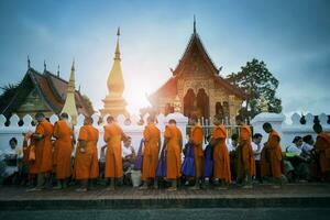 Luang Prabang lao-julio22,2023 ,monje a Luang Prabang recepción comida desde turista y aldeano en pueblo calle en contra hermosa wat sensoukharam templo uno de más importante sitio de luang prabang foto