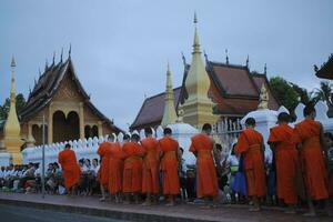 luang prabang Laos - 22 de julio de 2023 ,aldeano y turista ofrecimiento pegajoso arroz a budista monje en temprano Mañana a wat sensoukharam más famoso punto de referencia en luang prabang foto