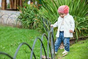 dulce año y un medio bebé niña a el jardín en un hermosa soleado día foto