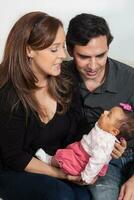 Portrait of young parents at home with their one month baby girl. Parenthood concept. Family love concept. photo