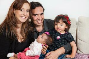 Portrait of young parents at home with their baby girls. Parenthood concept. Family love concept. photo