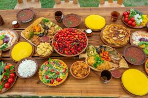 Homemade Romanian Food with grilled meat, polenta and vegetables Platter on camping. Romantic traditional moldavian food outside on the wood table. photo