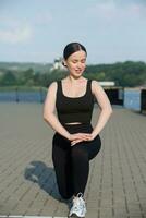 Young woman in black sportswear exercising outdoors. Fitness and healthy lifestyle concept. The white girl does sports in the park. photo