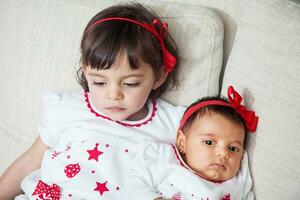 Big sister with her one month old baby sister at home. Love between sibblins concpet. Family concept. photo