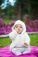 dulce seis meses antiguo bebé niña sentado a el jardín en un hermosa soleado día foto