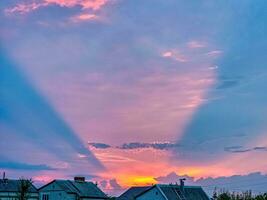 Unusual sunset. Pink conical optical effect from the rays of the setting sun in the clouds. photo