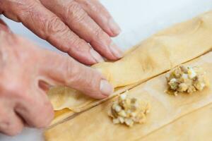Ravioli Preparation. Placing the upper dough strip to seal the ravioli photo