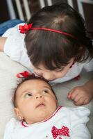 One month old baby girl at home with her big sister. Love between siblings concept. Family concept. photo