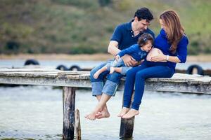 Young couple waiting for their second baby having fun with their baby girl at the beautiful white beach of Lake Tota located in the department of Boyaca at 3,015 meters above sea level in Colombia photo