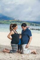 Young couple waiting for their second baby having fun with their baby girl at the beautiful white beach of Lake Tota located in the department of Boyaca at 3,015 meters above sea level in Colombia photo