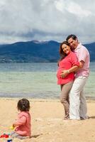 joven Pareja esperando para su segundo bebé teniendo divertido con su bebé niña a el hermosa blanco playa de lago total situado en el Departamento de boyaca a 3.015 metros encima mar nivel en Colombia foto