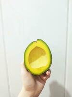 woman holding a slice of fresh ripe avocado photo